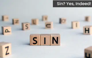 Sin spelled out by wooden block letters on a white background.