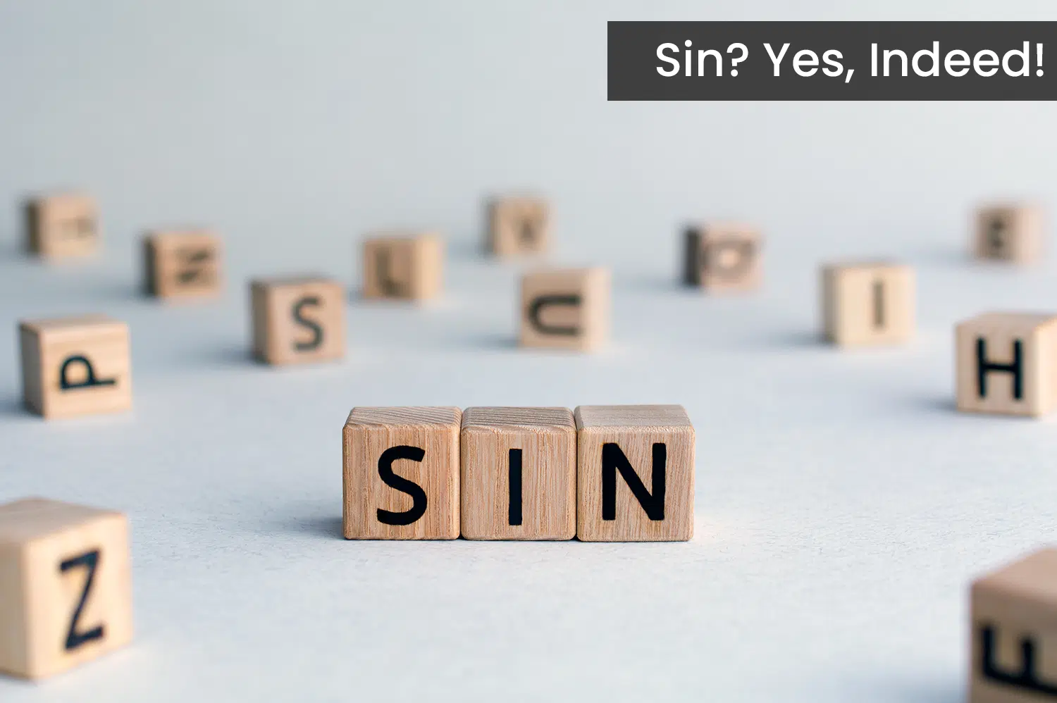 Sin spelled out by wooden block letters on a white background.