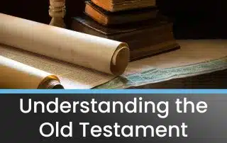 The old testament sitting on a table next to some books and a candle.