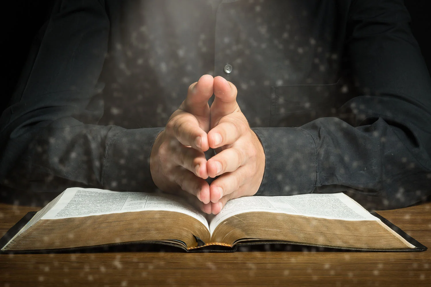 hands praying over an open bible